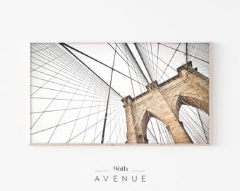 May include: A black and white photograph of the Brooklyn Bridge in New York City. The image is taken from a low angle, looking up at the bridge's steel cables and stone towers. The text "96th AVENUE" is printed below the image.