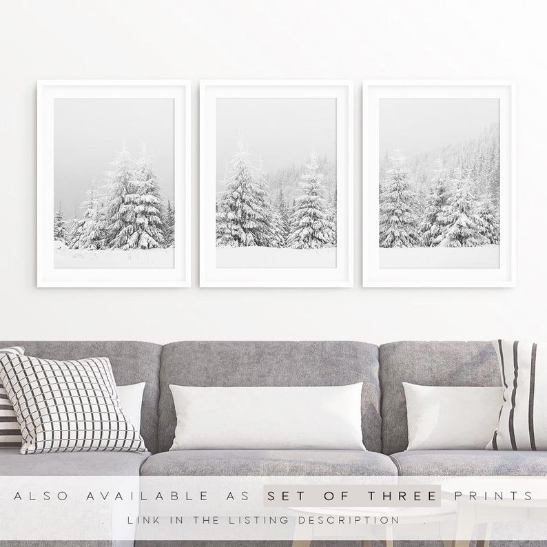 K&ouml;nnte beinhalten: Ein Set aus drei vertikalen Wandbildern in wei&szlig;en Rahmen, die jeweils eine schwarz-wei&szlig;e Winterlandschaft mit schneebedeckten Tannen zeigen. Der Text am unteren Rand lautet: ALSO AVAILABLE AS SET OF THREE PRINTS.
