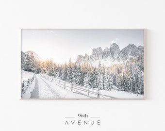 Könnte beinhalten: Eine schneebedeckte Berglandschaft mit einem Holzzaun und einem Weg, der durch die Bäume führt. Die Sonne scheint hell am Himmel und die Berge sind mit Schnee bedeckt.