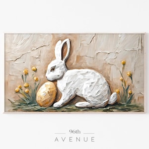 Peut inclure: Un lapin blanc avec un œuf doré est assis sur un fond beige texturé avec des fleurs jaunes. Le lapin est sculpté dans un style 3D, ce qui lui donne un aspect texturé. L'arrière-plan est peint avec un effet de coups de pinceau texturés.