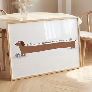 May include: A framed print featuring a cartoon dachshund with a long body, wearing sunglasses, and a small ball. The text "I love you soooooo much!" is written above the dog. The frame is light brown.