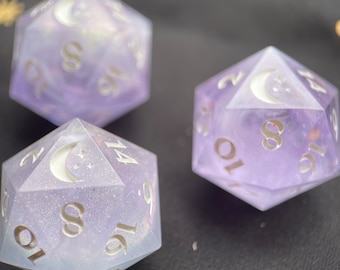 May include: Three purple and white dice with a crescent moon and star design. The dice are made of a translucent material and have a glittery finish.