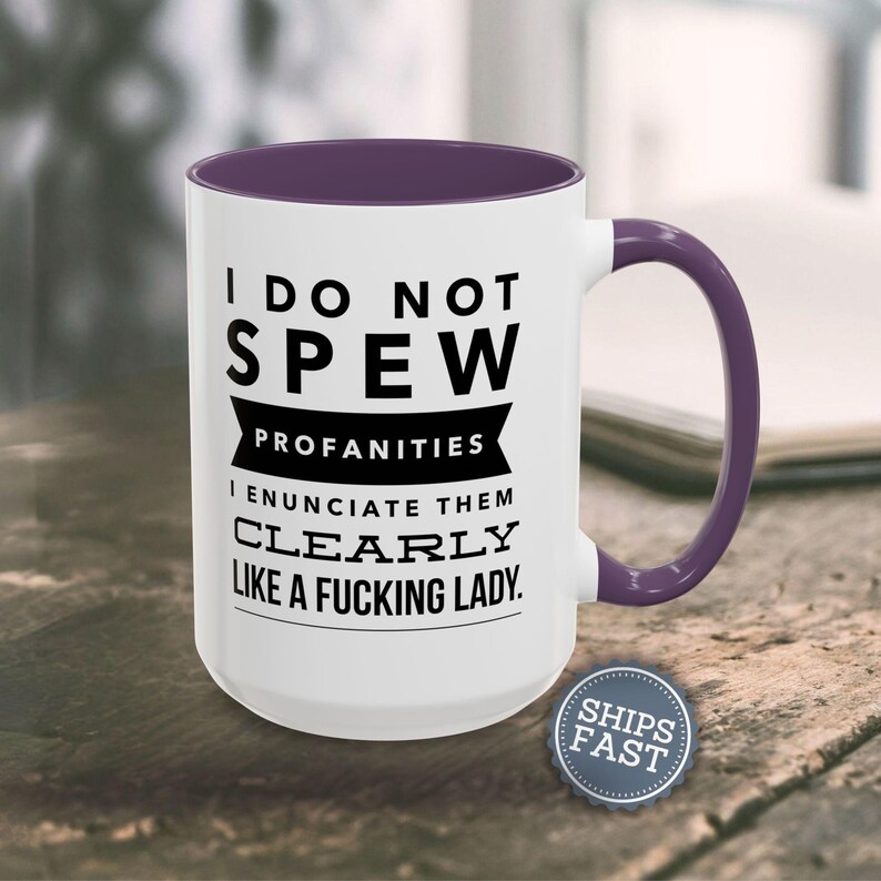 A white mug with a purple handle, featuring a humorous text that reads "I DO NOT SPEW PROFANITIES I ENUCIATE THEM CLEARLY LIKE A FUCKING LADY."