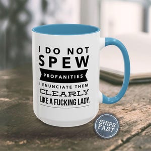A white and blue mug with a humorous text printed on it, placed on a wooden surface.