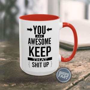 A white and red mug with the text "YOU ARE AWESOME KEEP THAT SHIT UP" printed on it, along with arrows pointing to the mug.