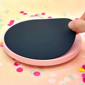 Pode incluir: Um prato girat&oacute;rio redondo rosa com uma parte superior circular preta remov&iacute;vel. O prato girat&oacute;rio est&aacute; sobre uma superf&iacute;cie com confete.