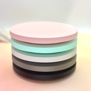 Pode incluir: Um conjunto de seis  tapetes redondos e coloridos. Os tapetes s&atilde;o em tons de rosa, cinza, branco e azul claro.