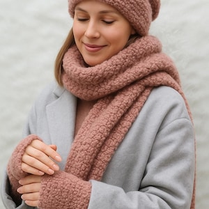 May include: A matching set of winter accessories in a soft rose color. The set includes a knitted beanie, a long scarf, and fingerless gloves. The items are made of a thick, textured yarn, perfect for cold weather.