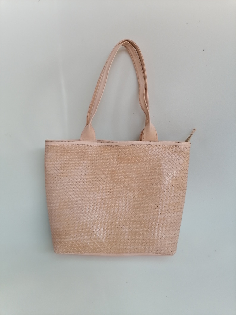 Op de afbeelding: Een lichtbeige geweven tote bag met twee handvatten.