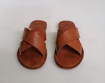 May include: A pair of brown leather sandals with criss-cross straps.