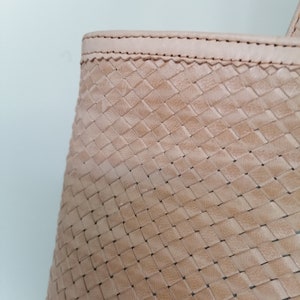 Op de afbeelding: Close-up van een lichtbruine geweven leren tote bag. De tas heeft een gestikte naad rond de bovenrand.