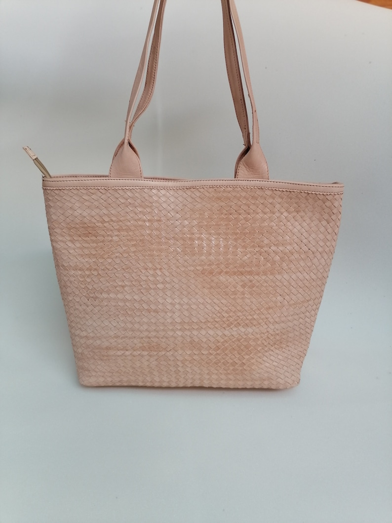 Op de afbeelding: Een lichtroze geweven leren tote bag met twee hengsels.