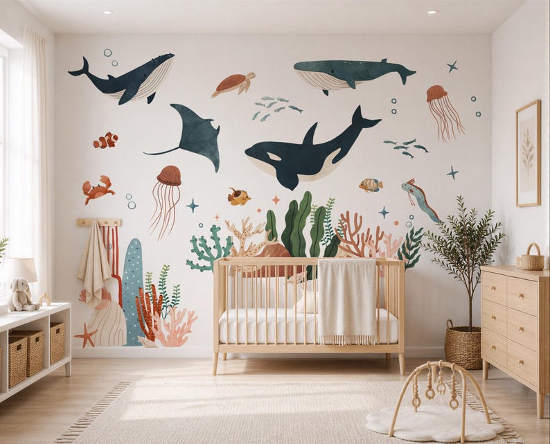 May include: A nursery with a wooden crib, dresser, and wall decals. The wall features colorful illustrations of marine life, including whales, a manta ray, and various fish. The room has a neutral color palette with a rug and a play mat.