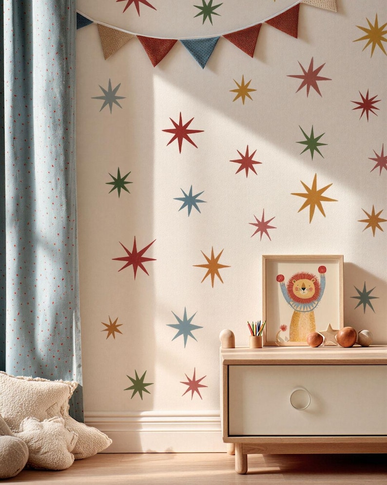 Puede incluir: Un conjunto de pegatinas de pared con formas de estrellas multicolores en tonos rojos, azules, verdes y amarillos. Las estrellas est&aacute;n dispuestas en un patr&oacute;n disperso sobre una pared clara, acompa&ntilde;adas por una guirnalda de banderines triangulares.