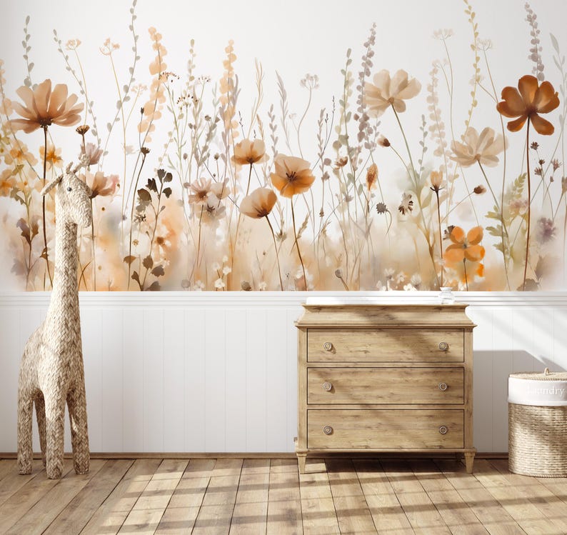 May include: A watercolor mural of wildflowers in shades of orange, brown, and beige adorns a white wall. A wooden dresser with three drawers and a woven giraffe statue stand in front of the wall. A woven basket sits to the right.