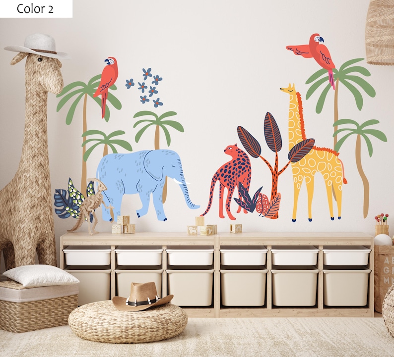 Op de afbeelding: Een muursticker set met een blauwe olifant, een gele giraf, een rode luipaard en twee rode papegaaien tussen groene palmbomen en donkerblauwe bloemen, inclusief diverse tropische planten in een vlakke, grafische illustratiestijl.