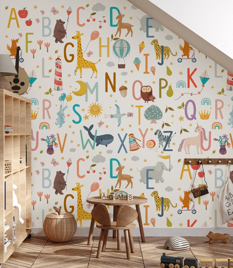 May include: A whimsical children's room with alphabet letters and animal illustrations on the wallpaper. The room features a wooden table and chairs, a wicker basket, and a toy train. The letters and animals are in various colors.