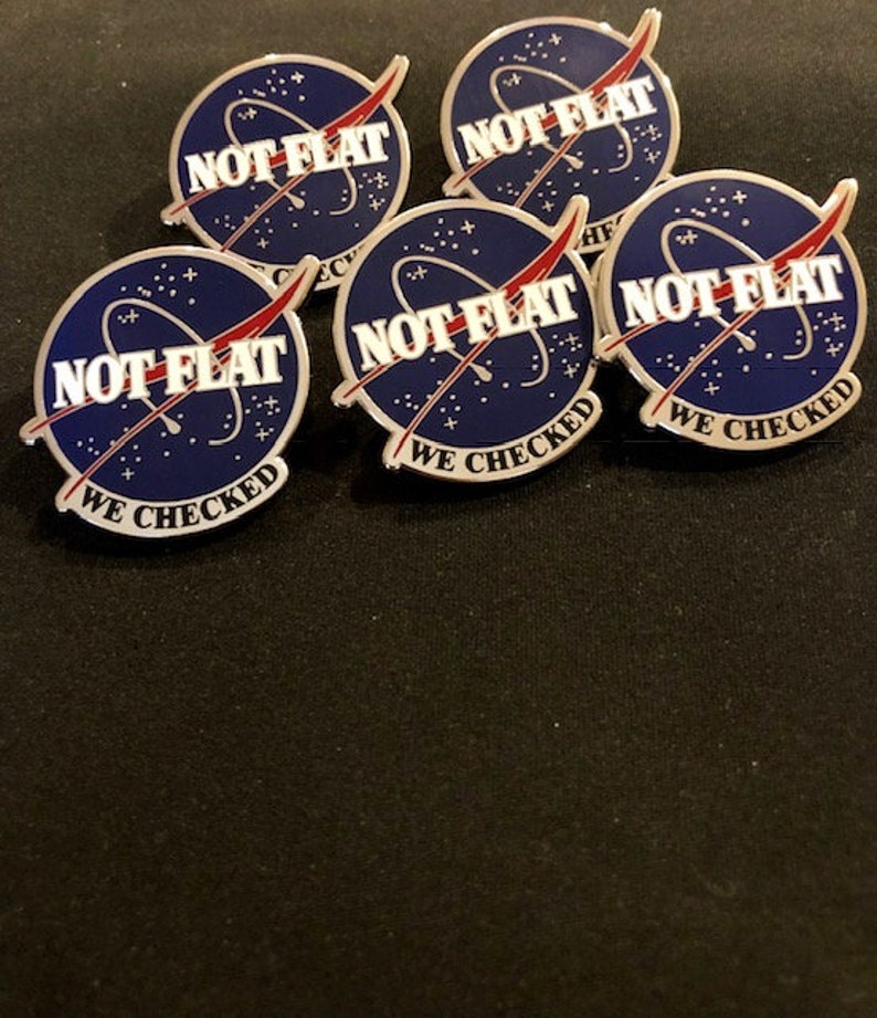 May include: Five silver pins with a blue and white NASA-style logo. The logo says "NOT FLAT WE CHECKED" in white text.