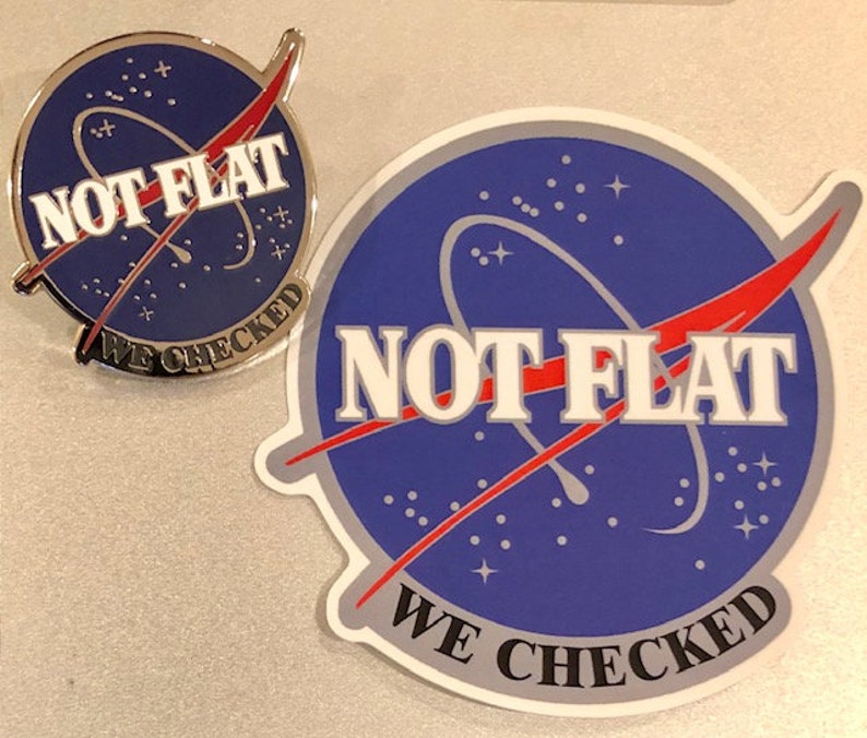 May include: A blue and white sticker with a red and white design. The sticker features a stylized image of a planet with a red and white orbit around it. The text "NOT FLAT WE CHECKED" is printed in white on the sticker.