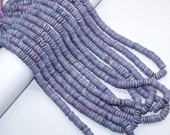 May include: A long strand of small, flat, circular disc-shaped beads in shades of light purple and lavender. The beads are strung together in a continuous line, featuring a matte texture and subtle variations in color throughout the strand.