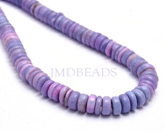 May include: A strand of round, flat, disc-shaped beads in varying shades of light and medium purple. The beads are strung together in a curved line. The text JMDBEADS is printed in light purple in the center of the image.