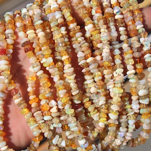 May include: Strands of gemstone beads in shades of orange, yellow, and white. The beads are small and irregular in shape, strung together to create necklaces. The gemstones have a natural, earthy appearance, with variations in color and texture.