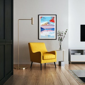 Puede incluir: Un sill&oacute;n amarillo con marco negro se encuentra frente a una impresi&oacute;n enmarcada de una escena de monta&ntilde;a con un lago y &aacute;rboles rojos. La impresi&oacute;n est&aacute; en una pared blanca con una l&aacute;mpara de pie y un jarr&oacute;n de flores en una mesa auxiliar.