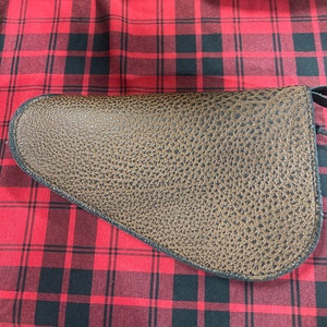 May include: A brown leather gun holster with a textured surface.