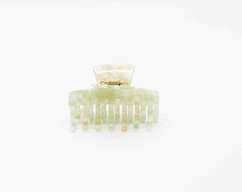 May include: A green and white marbled plastic hair claw with a gold spring.