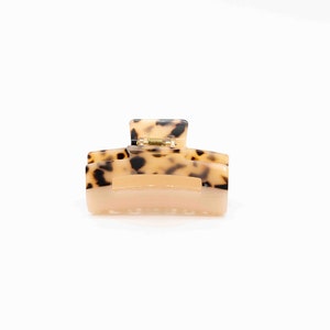 May include: A brown and black patterned hair claw clip with a gold spring.