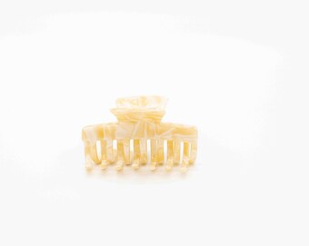 May include: A cream-colored plastic hair claw with a marbled pattern.
