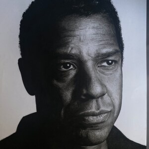 May include: Black and white pencil drawing of a man's face. The man has a serious expression and is looking directly at the viewer. The drawing is signed "donna 2013" in the bottom right corner.