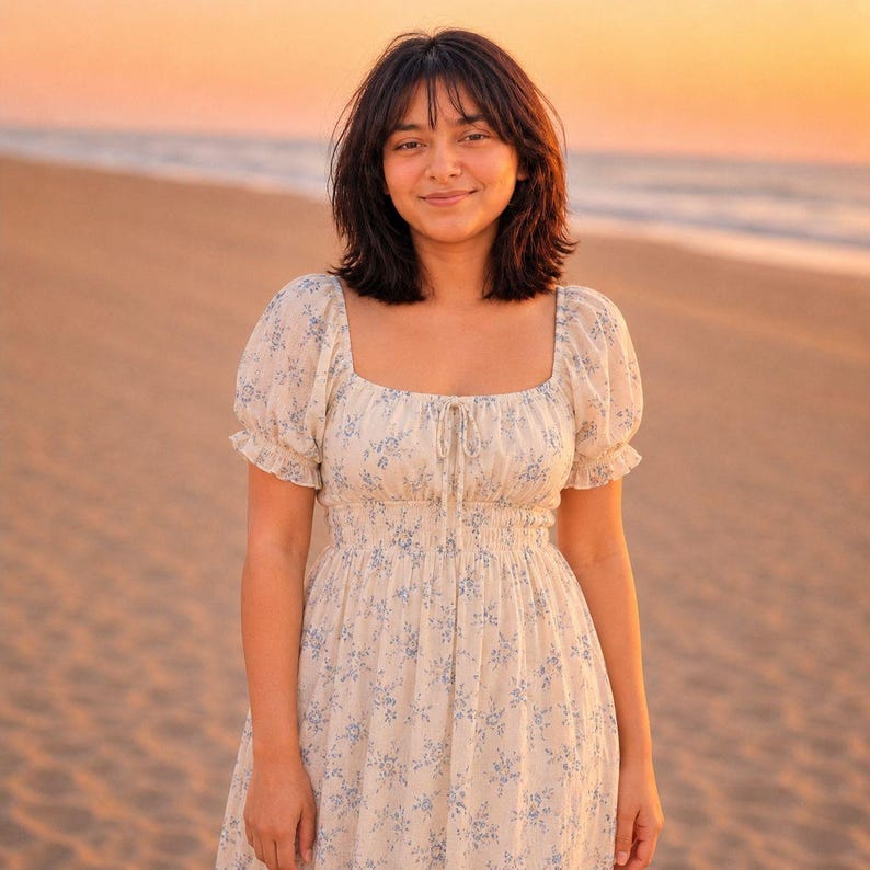 May include: A cream-colored midi dress featuring a delicate blue floral print, a square neckline with a center tie detail, short puff sleeves with ruffled edges, and a smocked bodice that transitions into a flowing skirt with a soft silhouette.