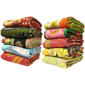 May include: A stack of ten colourful kantha quilts with floral and geometric patterns. The quilts are made from recycled saris and are hand-stitched.