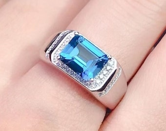 May include: A silver ring with a large blue gemstone surrounded by smaller white gemstones.
