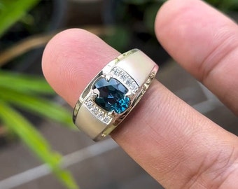May include: A silver ring with a blue oval gemstone surrounded by smaller white gemstones.
