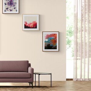 May include: Three framed abstract paintings with colourful swirls and splashes of colour hang on a beige wall above a brown sofa and a black side table.