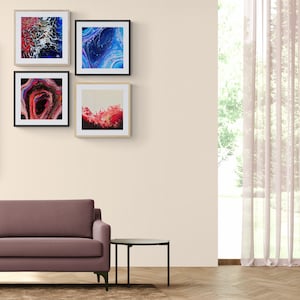 May include: A living room interior with a mauve sofa, a black side table, and a brown rug. Four framed abstract paintings hang on the wall behind the sofa. The paintings feature blue, red, and white colors.