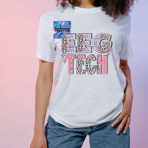 Könnte beinhalten: Weißes T-Shirt mit dem Text "EEG TECH" in rosa und lila Buchstaben mit Leopardenmuster. Die Buchstaben sind schwarz umrandet. Auf jeder Seite des Textes befinden sich zwei kleine Sterne.