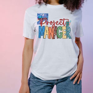 May include: White t-shirt with a rainbow design that says "Project Manager" with a coffee cup graphic.