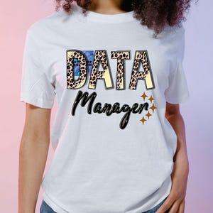 May include: White t-shirt with the words "DATA Manager" in a bold, eye-catching design. The word "DATA" features a leopard print pattern and blue watercolor effect, while "Manager" is in a stylish script font. Four gold stars are below the word "Manager".