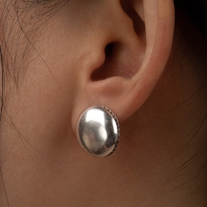 May include: A pair of silver round stud earrings with a textured edge.