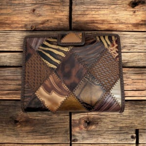 May include: A patchwork leather wallet featuring a variety of animal print patterns in shades of brown, tan, and black. The wallet has a rectangular shape with a snap closure and a brown border.