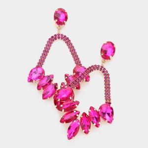 May include: A pair of pink crystal earrings with a gold-tone setting. The earrings feature a cascading design of marquise-shaped crystals and a curved, open-circle design.