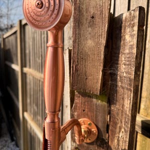 Może przedstawiać: Biały ceramiczny kubek z czarnym uchwytem i napisem "But First, Coffee" pogrubioną czcionką. Kubek jest wypełniony ciemnym płynem, prawdopodobnie kawą, i stoi na jasnej powierzchni.