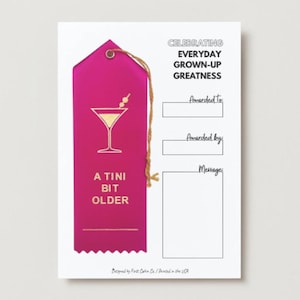 May include: A magenta ribbon-shaped award card with gold text and a martini glass illustration. The card reads "A Tini Bit Older" and "Celebrating Everyday Grown-Up Greatness". Includes space to write "Awarded To", "Awarded By", and "Message".