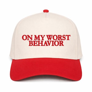May include: A baseball cap with a white crown and a red brim. The text "ON MY WORST BEHAVIOR" is printed in red across the front of the cap. The cap has a red button on top.