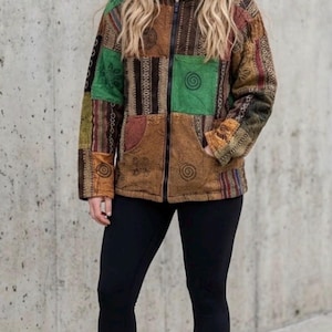 May include: A long-sleeve zip-up jacket featuring a patchwork design of brown, green, and maroon fabric panels with spiral and geometric patterns, paired with solid black leggings and plain white athletic sneakers.