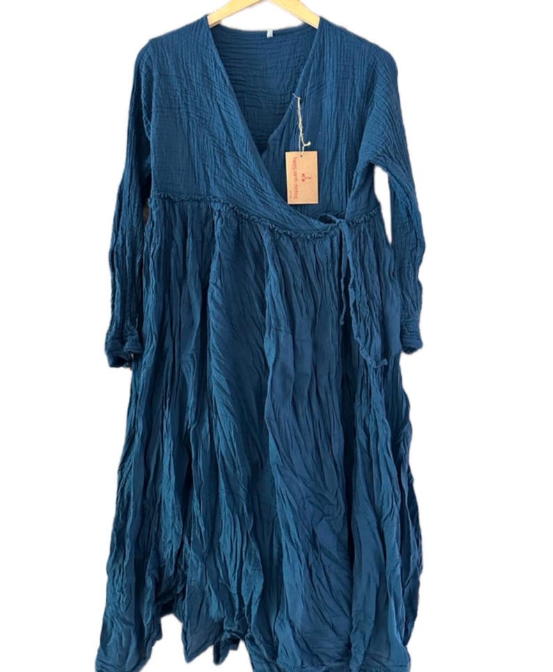 May include: A long-sleeved, deep blue wrap dress with a V-neckline and a textured, crinkled fabric finish. The dress features a side tie closure at the waist and a flowing, loose-fitting skirt. A small rectangular brown paper tag is attached.