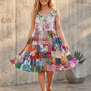 May include: A sleeveless knee-length dress featuring a V-neckline and a vibrant patchwork design. The bodice displays a floral pattern, while the skirt consists of multiple horizontal tiers of various colorful fabric squares in diverse prints.